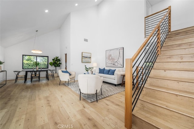 living room featuring high vaulted ceiling, recessed lighting, visible vents, stairway, and wood-type flooring