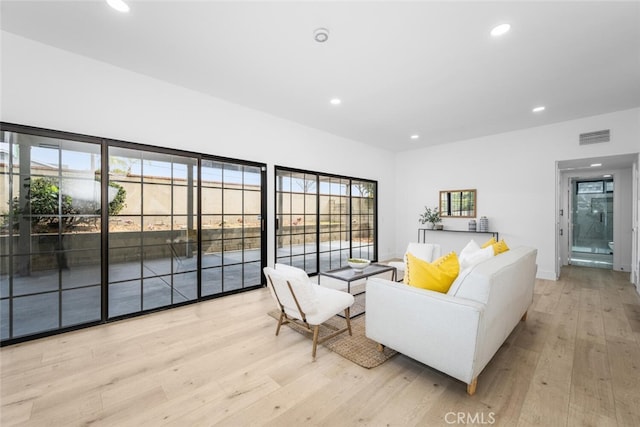 living area featuring light wood-type flooring, visible vents, and recessed lighting