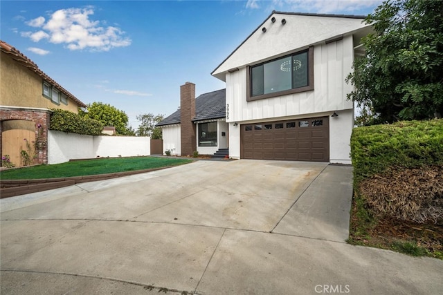 view of front of property with concrete driveway, a chimney, an attached garage, a front lawn, and stucco siding