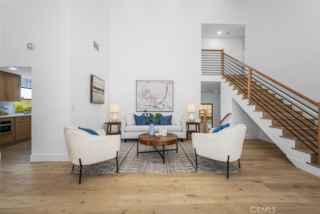 living area with light wood-style floors, stairs, a high ceiling, and visible vents