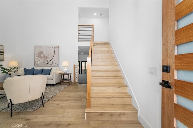 stairs featuring a high ceiling, wood finished floors, and baseboards