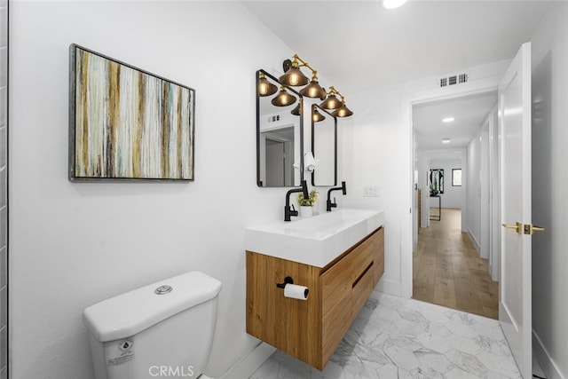 bathroom featuring marble finish floor, visible vents, vanity, and toilet