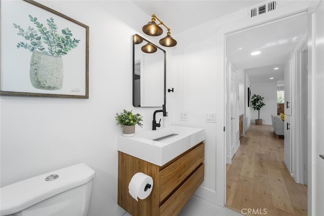 bathroom with visible vents, vanity, toilet, and wood finished floors