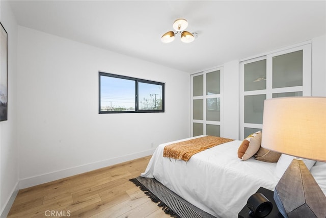 bedroom featuring a chandelier, wood finished floors, and baseboards