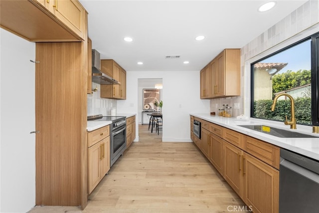 kitchen with visible vents, wall chimney exhaust hood, appliances with stainless steel finishes, a sink, and backsplash