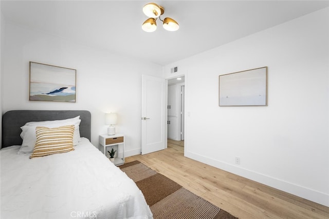 bedroom with an inviting chandelier, baseboards, and wood finished floors