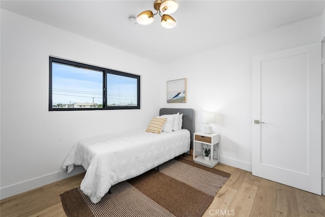 bedroom featuring light wood-style floors, baseboards, and a chandelier