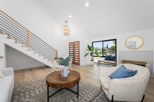 living room featuring baseboards, stairway, wood finished floors, baseboard heating, and high vaulted ceiling