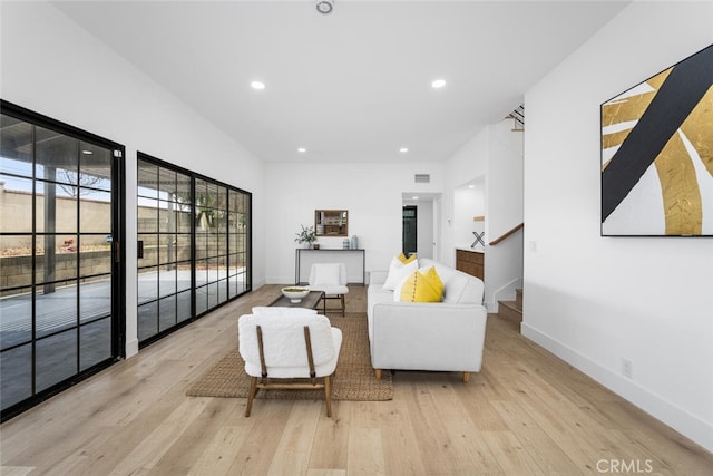 living area with recessed lighting, visible vents, baseboards, light wood-style floors, and stairway