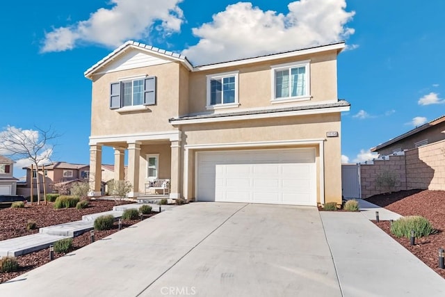 traditional home with driveway, an attached garage, fence, and stucco siding