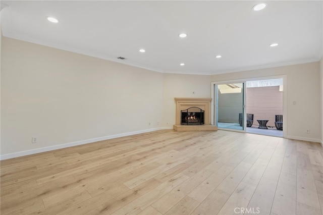 unfurnished living room with visible vents, crown molding, a lit fireplace, and light wood finished floors