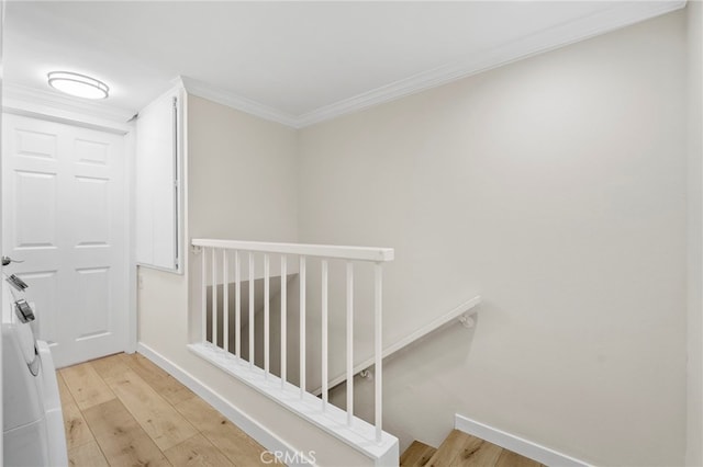 hallway with light wood-style floors, baseboards, crown molding, and an upstairs landing