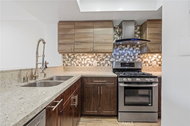 kitchen featuring wall chimney exhaust hood, stainless steel range with gas cooktop, tasteful backsplash, and a sink