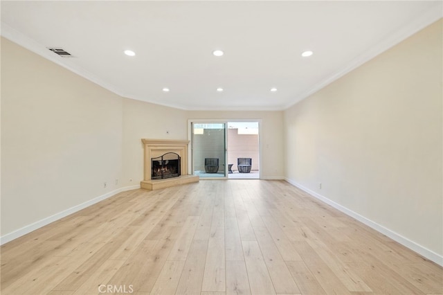 unfurnished living room with a fireplace with raised hearth, baseboards, visible vents, and crown molding