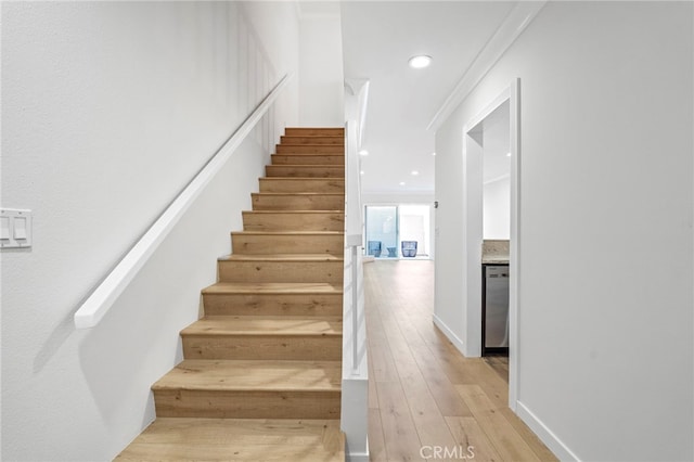 stairs with wood-type flooring, ornamental molding, and recessed lighting