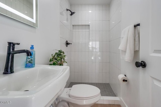 bathroom featuring a sink, a tile shower, and toilet