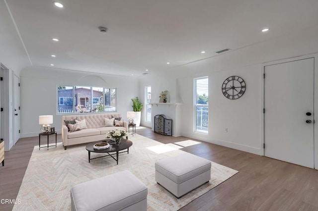 living area with recessed lighting, a fireplace, visible vents, and light wood-style floors