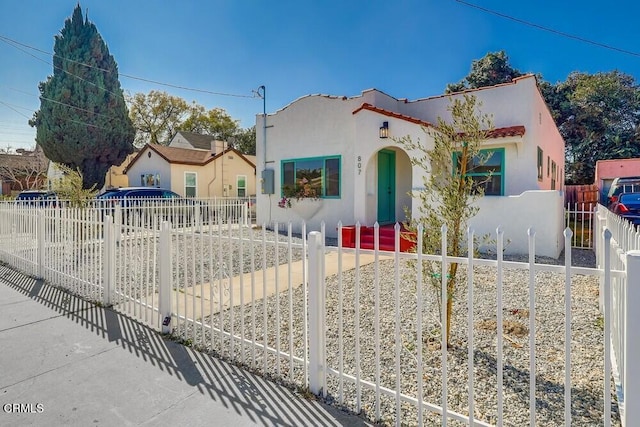 mediterranean / spanish home featuring a fenced front yard and stucco siding