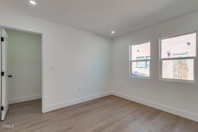 empty room with light wood-style floors, recessed lighting, and baseboards