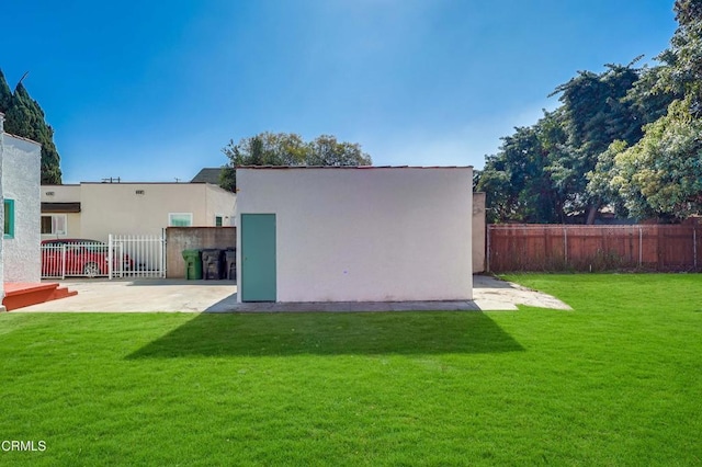 back of house featuring stucco siding, a yard, an outdoor structure, and fence