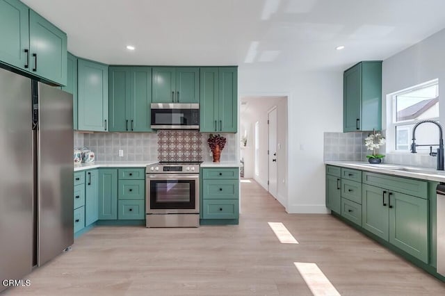 kitchen featuring green cabinetry, stainless steel appliances, a sink, and light countertops