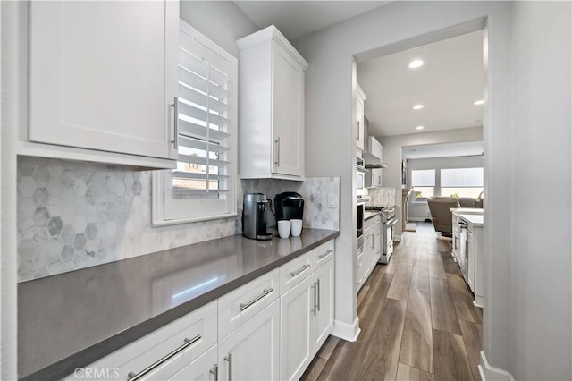 kitchen featuring white cabinets, decorative backsplash, dark countertops, dark wood-style floors, and recessed lighting