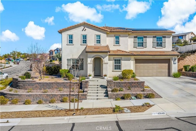 mediterranean / spanish house with solar panels, driveway, a tiled roof, and stucco siding