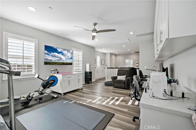 exercise room with a ceiling fan, a wealth of natural light, light wood-style flooring, and recessed lighting