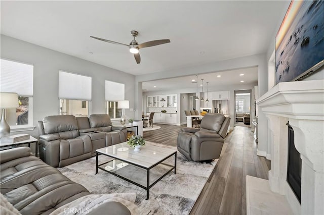 living area featuring ceiling fan, a premium fireplace, light wood-type flooring, and recessed lighting