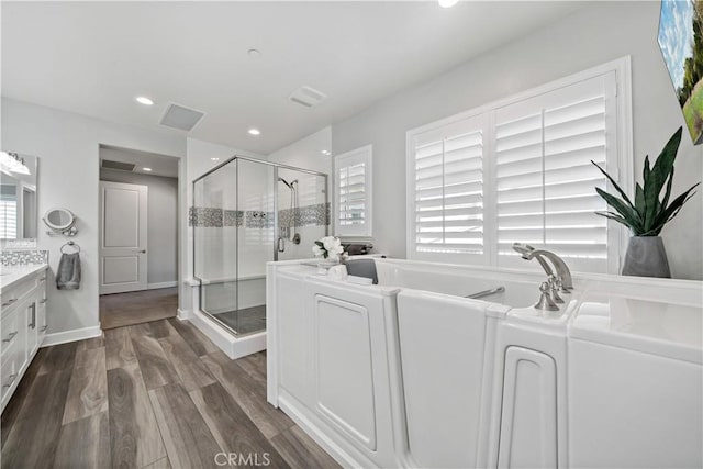 full bath with recessed lighting, wood finished floors, vanity, a shower stall, and a bath