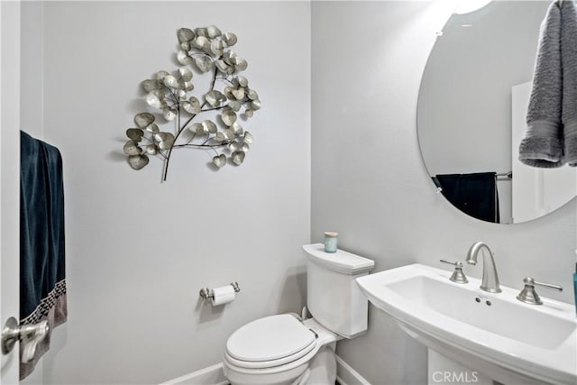 bathroom featuring baseboards, a sink, and toilet