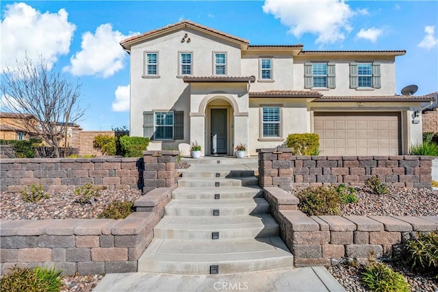 mediterranean / spanish-style house with a tiled roof, an attached garage, and stucco siding