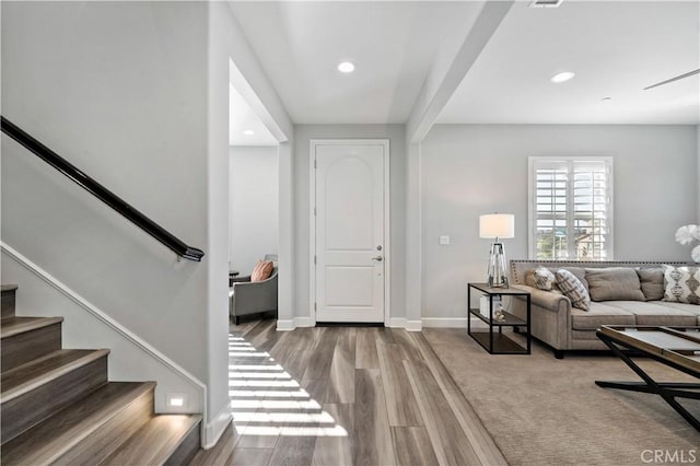 living area with baseboards, stairway, wood finished floors, and recessed lighting