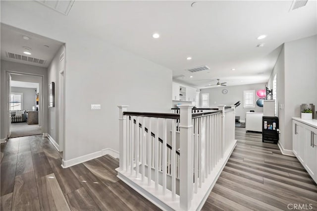 hallway featuring visible vents, an upstairs landing, and wood finished floors