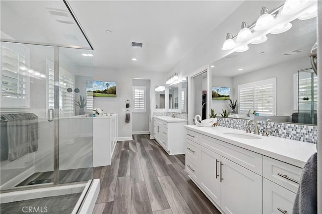 full bathroom featuring visible vents, a sink, backsplash, and a shower stall