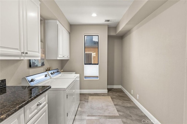 washroom with cabinet space, plenty of natural light, baseboards, visible vents, and washing machine and clothes dryer