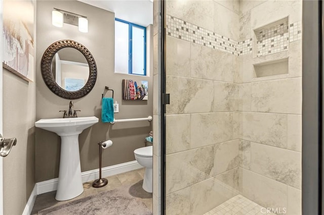 full bath featuring a sink, a shower stall, toilet, and baseboards