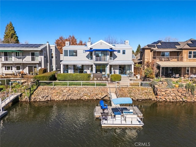 back of house with a water view, a balcony, a fenced backyard, and a patio area