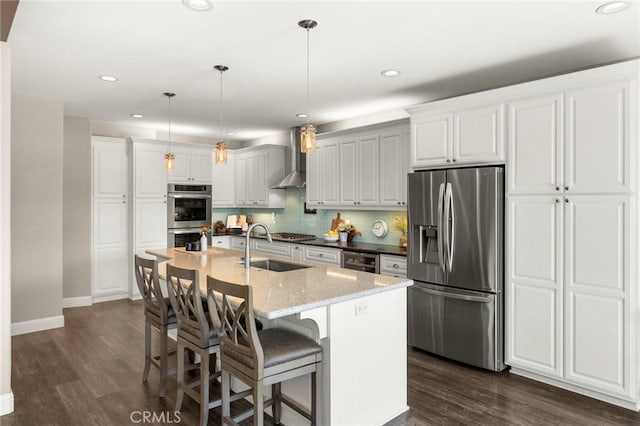 kitchen featuring dark wood-type flooring, wall chimney exhaust hood, stainless steel appliances, and a sink