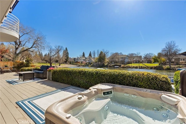 deck with a residential view, a water view, and an outdoor hot tub