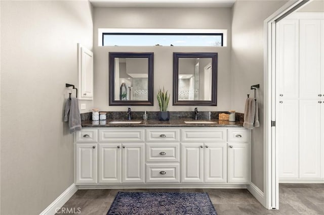 full bath featuring a sink, baseboards, and double vanity