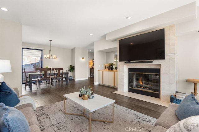 living room featuring a notable chandelier, a fireplace, recessed lighting, wood finished floors, and baseboards