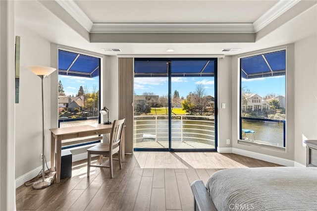 bedroom featuring access to exterior, a tray ceiling, ornamental molding, and wood finished floors