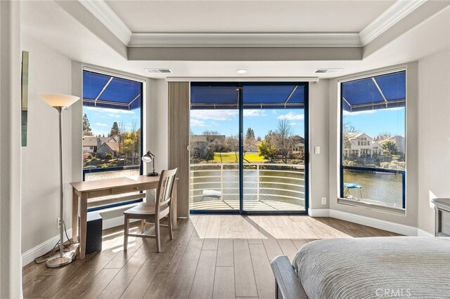 bedroom with a raised ceiling, wood finished floors, access to outside, and ornamental molding