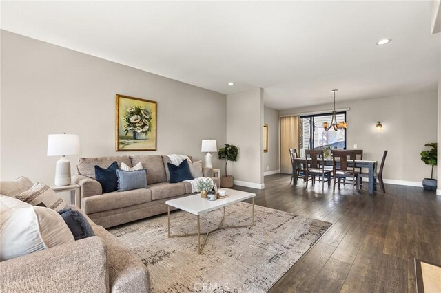 living area with baseboards, a notable chandelier, dark wood-type flooring, and recessed lighting