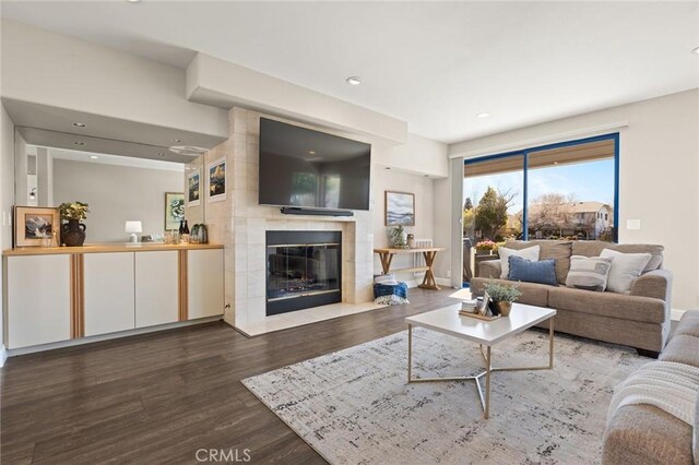 living area featuring a fireplace, wood finished floors, baseboards, and recessed lighting