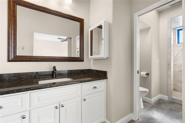 bathroom with toilet, baseboards, tiled shower, and vanity