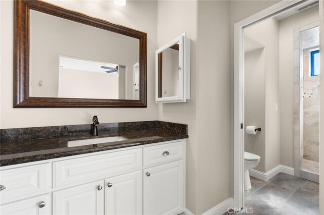 full bathroom with a tile shower, baseboards, toilet, and vanity