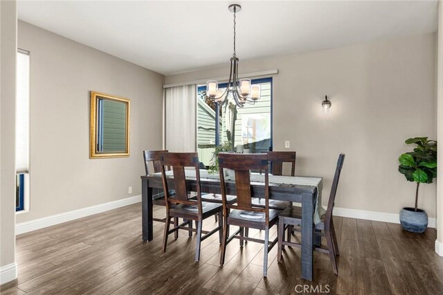 dining space with baseboards, a notable chandelier, and wood finished floors