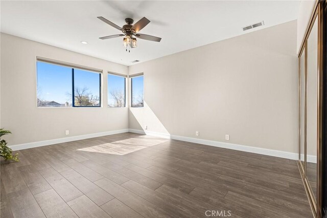 unfurnished room featuring dark wood finished floors, visible vents, baseboards, and ceiling fan